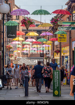 Coloured umbrellas suspended above shoppers in Coppergate shopping centre, York, UK. Stock Photo