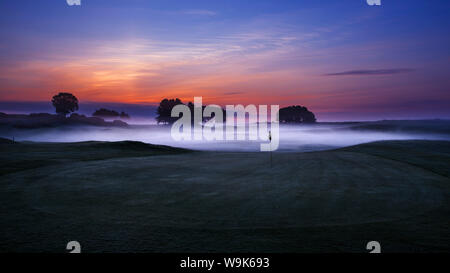 Dawn sky extending beyond the mist low lying in the sunken fairways of Delamere Forest Golf Club on a spring morning, Cheshire, England, UK Stock Photo