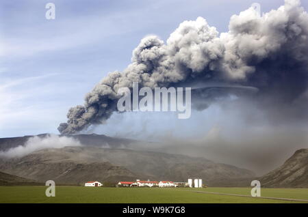 Farm buildings and green fields with the ash plume of the Eyjafjallajokull eruption in the distance, near Hella, southern area, Iceland, Polar Regions Stock Photo