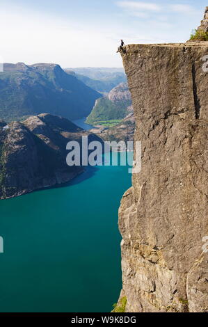 Man sitting on Preikestolen (Pulpit Rock) above fjord, Lysefjord, Norway, Scandinavia, Europe Stock Photo