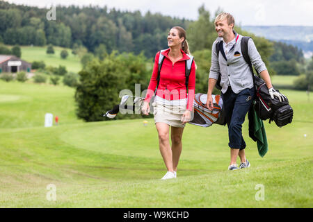 Golfing couple walking together on golf course Stock Photo