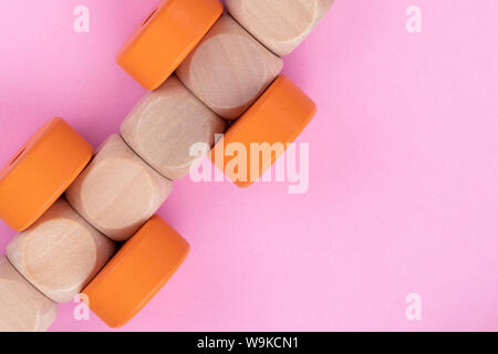 Top view on kids educational game on light pink paper background. Wooden train made from cubes, orange circles. Close up. Stock Photo