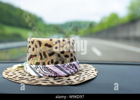 leopard hat man with bandana on the dashboard of a car on the road Stock Photo