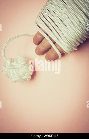 a hand with string wrapped round it and coiled in a ball at the other end. Stock Photo