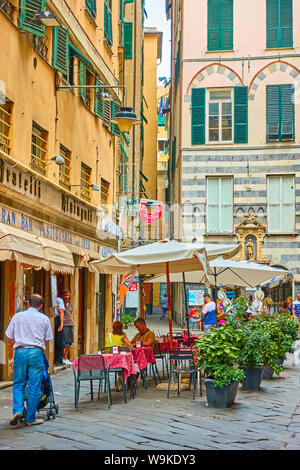 Genoa, Italy - July 06, 2019: Old street in Genoa and people in cafe Stock Photo