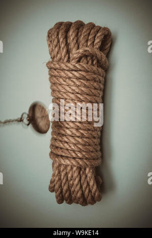 an old pocket watch swinging above a bound length of rope, symbolic of time up, imminent death, hangman's noose. Stock Photo