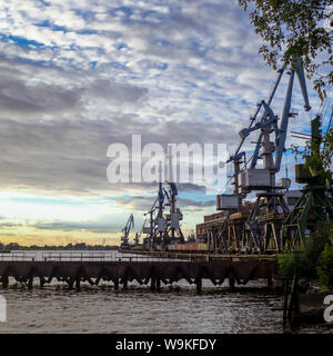 Cranes loading coal from train containers in Riga industrial port. Stock Photo