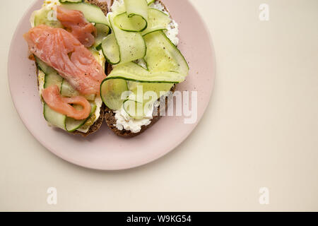 Sandwich with salmon, cucumber, cheese and rye bread close-up on white background. Diet and obesity concept Stock Photo