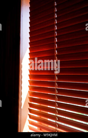 Closed orange plastic blinds with sunlight in the morning. window with blinds. Interior design of living room with window horizontal blinds. Window Stock Photo