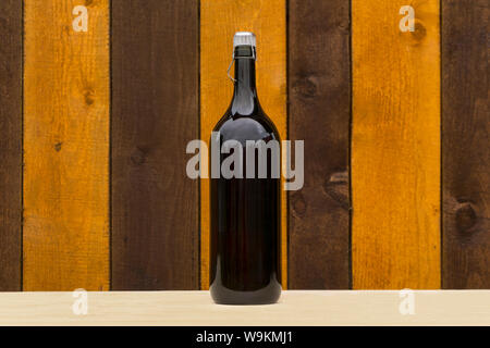 corked bottle of dark glass with home wine stands on a shelf against the background of a wooden wall Stock Photo