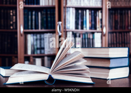 Books lie on the table against the background of bookcases. Stock Photo