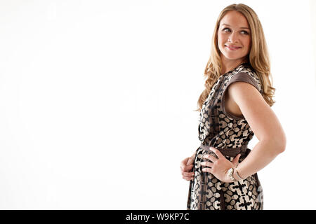 Mid-adult woman standing with hand on hip, looking over shoulder. Stock Photo