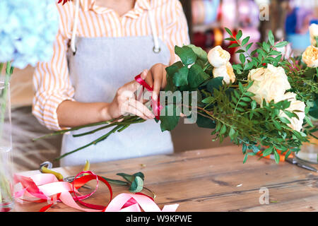 Hands of Caucasian woman wrapping bouquet in brown paper stock photo