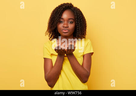 Beautiful charming african american woman blowing a kiss with hand on air, expresses love and warm feeling. close up photo. I love you and miss you. c Stock Photo