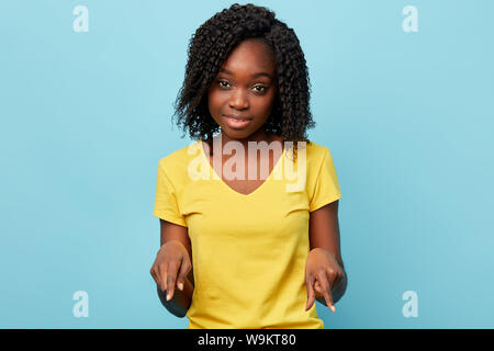 pleasant lovely stylish girl showing to the floot. look here. studio shot. direction. place for advertisement. Stock Photo