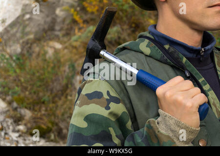 geologist outdoor holds a geological hammer in his hand on his shoulder Stock Photo