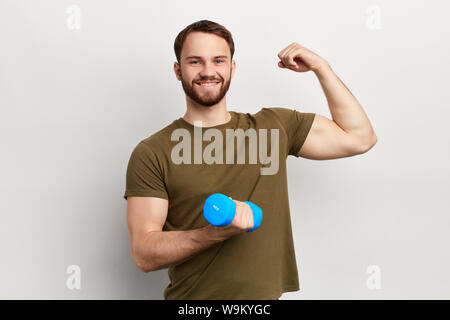 Satisfied young cheerful positive strong man lifting dumbbell isolated on white background. lifestyle, hobby, free time, spare time. happiness Stock Photo
