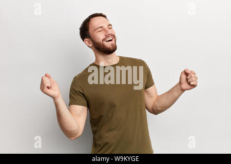 satisfied young positive man celebrating success isolated over white background. happiness, facial expression. Stock Photo