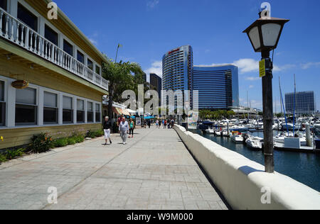 Unidentified visitors walk along the Seaport Village, a waterfront shopping and dining area, on a beautifu Stock Photo