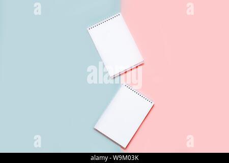 Two notebooks with blank white sheets on a pink and blue background Stock Photo