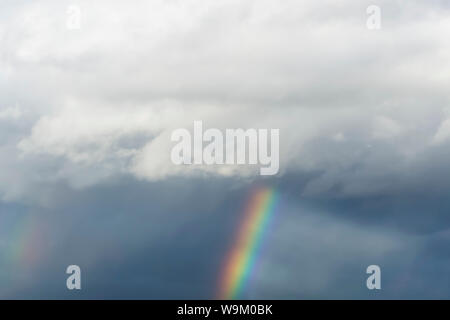 rainbow against the gray clouds of stormy sky Stock Photo