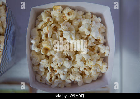 A wide classic box of theater popcorn isolated on white . Popcorn spilled from a striped box . Three vintage-style boxes of popcorn in a carnival them Stock Photo