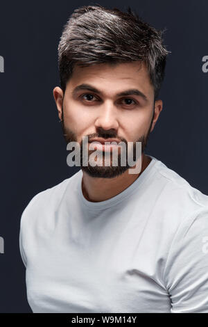 handsome stylish attractive man looks confidently, dressed in casual trendy white t shirt, isolated over black background. Young sport trainer poses t Stock Photo