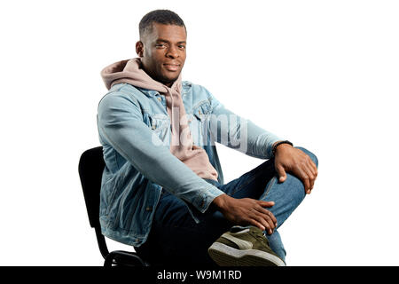 Stylish handsome dark-haired man sitting on a chair, crossing his legs and looking at the camera isolated over white background. copy space Stock Photo