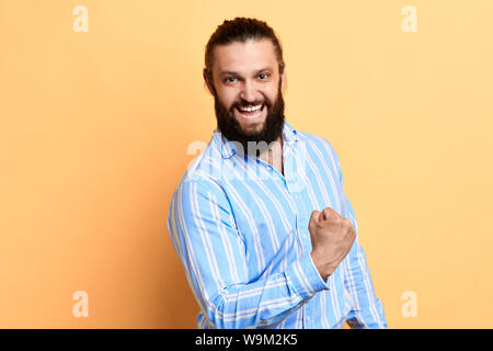 young bearded man celebrating victory over yellow background, feeling , emotion, happiness. I've done it. Stock Photo