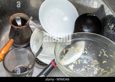 Dirty dishes in the sink. Dirty cook, turk, cup, bowl, spoons in sink Stock Photo