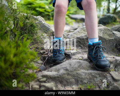 5 year old boy descends a rocky incline in walking boots, legs and feet only. Stock Photo