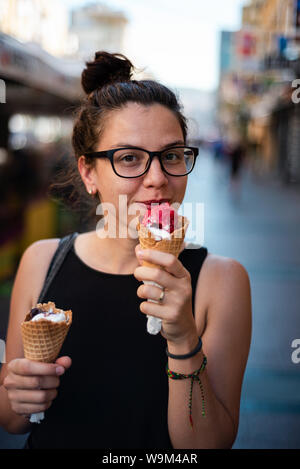 Cute hipster girl eating two ice creams on the street Stock Photo