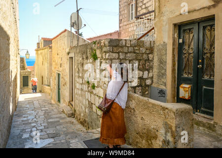 A woman takes a photo inside the ancient walls of Dubrovnik, Croatia on a sunny summer day Stock Photo