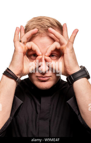 Young blond man in a black shirt, watches and bracelet is making faces, isolated on a white background Stock Photo