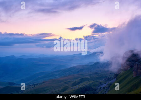 Sunset in the mountains. The sun shines through the fog over the mountain range. North Caucasus Russia