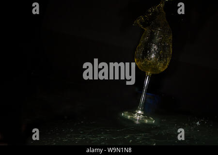 Splash with white wine and receiving cup through which the drops of straw yellow liquid slide Stock Photo