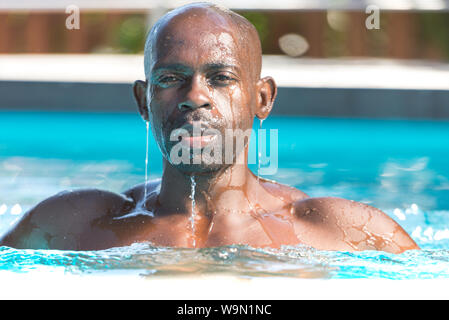 African adult male swimming in pool coming out of water dripping Stock Photo