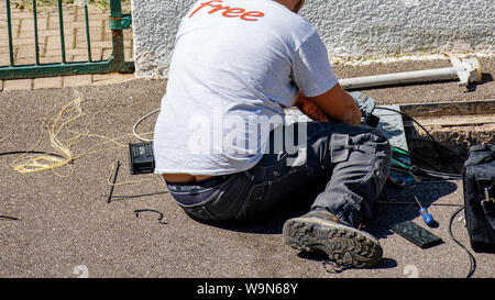 Paris, France - Jun 13, 2019: Unrecognizable man installing internet optic fiber for Free French operator in city manhole, Stock Photo