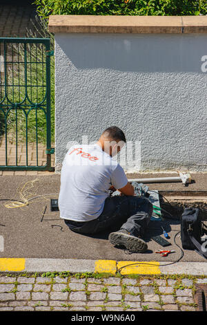 Paris, France - Jun 13, 2019: Elevated view of unrecognizable man installing internet optic fiber for Free French operator in city manhole Stock Photo