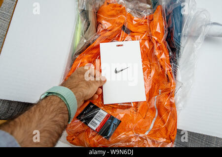 Paris, France - Jun 28, 2019: Man hand unboxing new Nike Running clothes looking at the Nike logotype on the greeting present card Stock Photo
