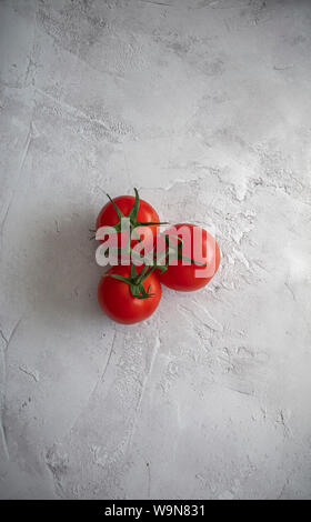 Food photography - overhead view of three large red tomatoes on the vine on plain white textured background Stock Photo