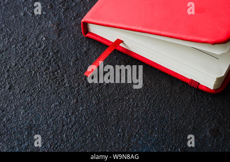 Red closed notebook for writing or book on dark background. Stock Photo