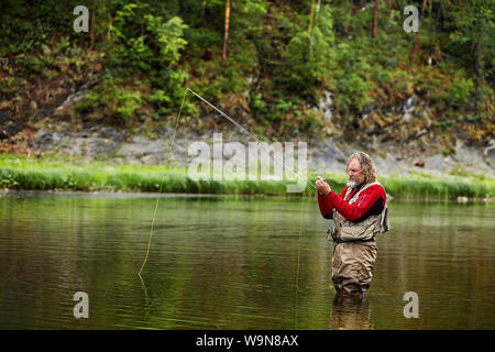 A man with a beard is fishing for spinning in the river Stock Photo - Alamy