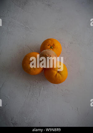Food photography - view from above of three oranges with an onion on top and a plain textured rustic white background Stock Photo