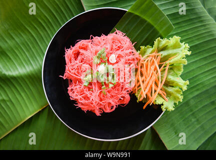 Rice vermicelli pink frying and vegetable / Stir fried rice noodles with red sauce served on plate on banana feaf , Thai Asian style noodles Stock Photo