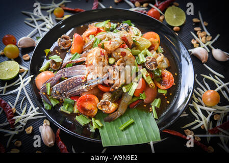 Seafood salad spicy with fresh shrimp crab cockles served on black plate fresh vegetables herbs and spices ingredients with chilli tomato peanut garli Stock Photo