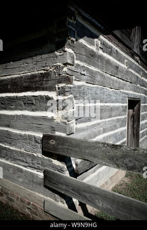 A close up of the hand-hewn log cabin with wooden fence attached at corner in the Southeastern USA Stock Photo