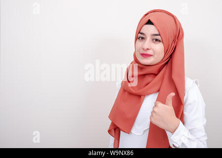 Hijab muslim woman showing thumbs up gesture with hand. Approving expression looking at the camera Stock Photo