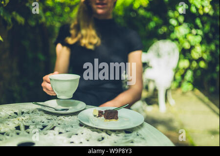 A young woman is drinking coffee and eating cake in a cafe Stock Photo