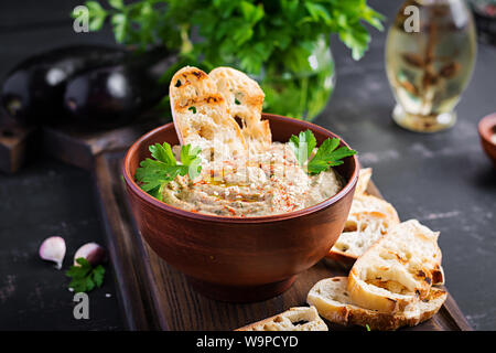 Baba ghanoush vegan hummus from eggplant with seasoning, parsley and toasts. Baba ganoush. Middle Eastern cuisine. Stock Photo